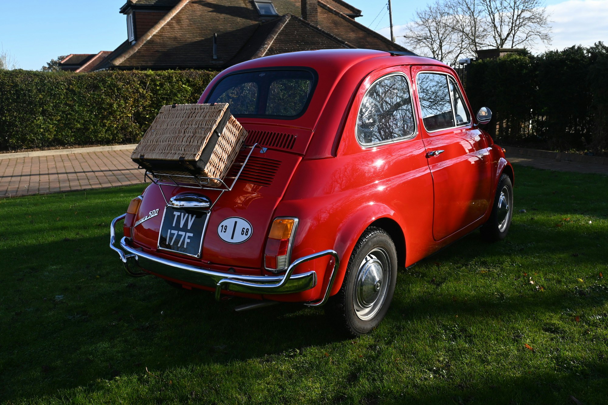 Classic Red Fiat 500 motor car with picnic basket parked on